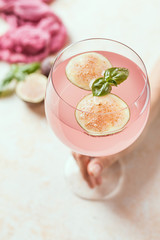 Pink cocktail with fig and basil on light background close up