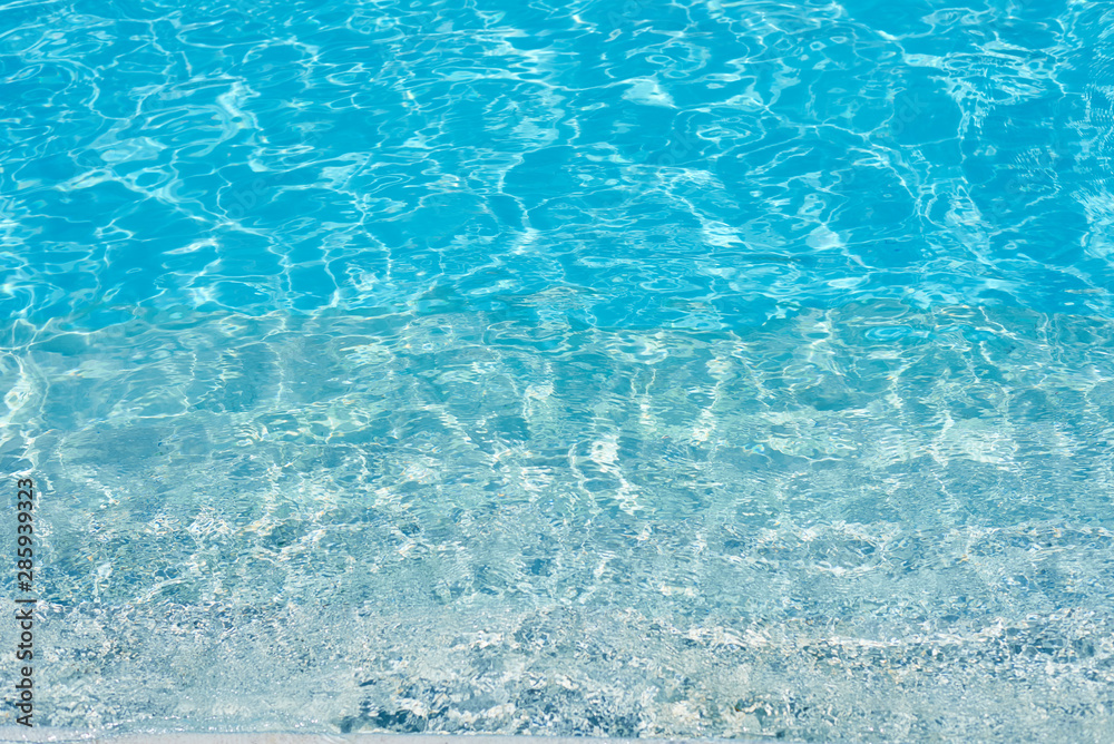 Wall mural background of water in blue swimming pool, water surface with a sun reflection