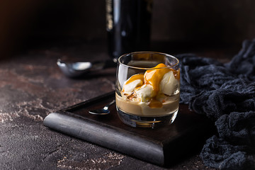 Ice cream with caramel topping and Irish cream liqueur in a glass over dark background. - obrazy, fototapety, plakaty