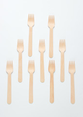 A lot of eco-friendly wooden forks on a white background. Minimalistic eco concept