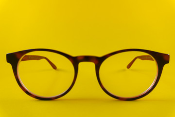 Brown-red, round glasses on yellow background