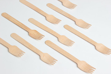 Many eco-friendly wooden forks on a white background. Minimalistic eco concept