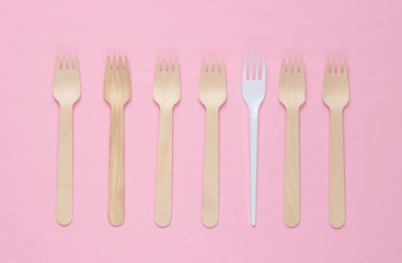 Minimalistic environmental concept. Wooden and plastic forks on a pink pastel background. Creative eco background