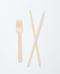 Eco cutlery. Chinese chopsticks, wooden fork on white background. Top view