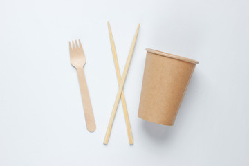 Eco-friendly cutlery. Chinese chopsticks, wooden fork, craft paper cup on white background. Minimalism eco concept.Top view