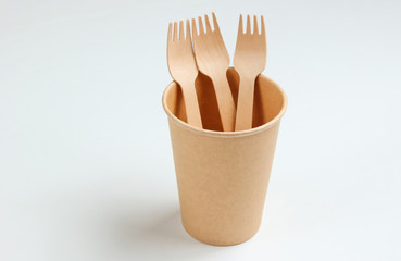 Disposable empty coffee cup with forks of natural materials on white background. Eco friendly concept. Top view