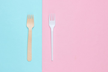 Minimalistic environmental concept. Wooden and plastic forks on a pink blue pastel background. Creative eco background