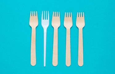 Minimalistic environmental concept. Wooden and plastic forks on a pink blue background. Creative eco background. Top view
