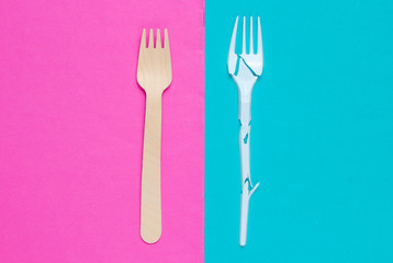 Minimalistic ecologically clean still life. Pop Art. Broken plastic fork and wooden fork on blue pink background. Cutlery made from natural materials, Top view