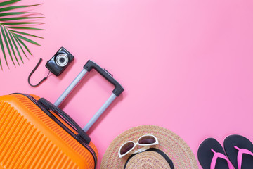 Flat lay orange suitcase with traveler accessories on soft pink background. travel, summer and holiday concept.
