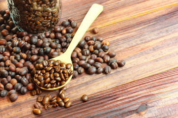 top view dried coffee beans with roasted coffee beans .coffee beans on wood spoon on brown wood floor,copy space.