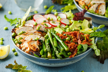Cobb salad bowl with grilled chicken breast, asparagus, avocado, radishes and bacon