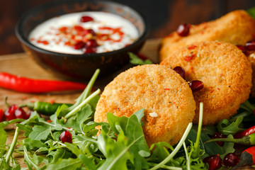 Thai food spicy fish cakes served with pomegranate seeds and wild rocket, arugula salad.