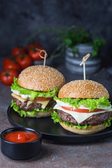 Hamburger with beef meat burger and fresh vegetables on dark background. Tasty fast food.