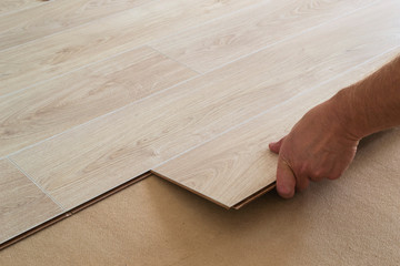 Man laying laminate flooring in a home.