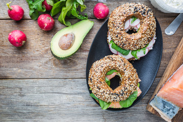 Bagels with cream cheese avocado, fish, arugula and radish. Healthy breakfast food. Top view.