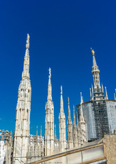 Fototapeta na wymiar White marble statues on the roof of famous Cathedral Duomo di Milano in Italy