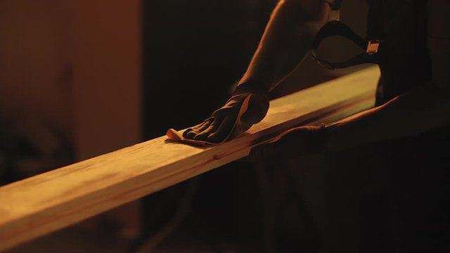 Close up of man`s hands polishing wood at sunset light. Woodworking, carpentering, craft, profession concept.