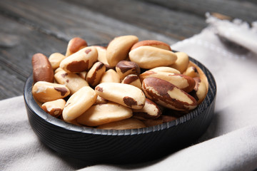 Plate with tasty Brazil nuts and fabric on table