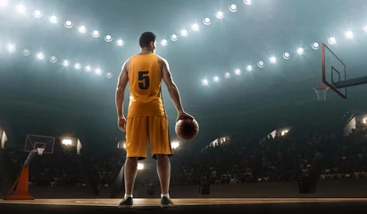 Fotobehang Basketball player in sports uniform on empty floodlit basketball court with the ball © TandemBranding