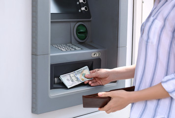 Woman taking money from cash machine outdoors, closeup