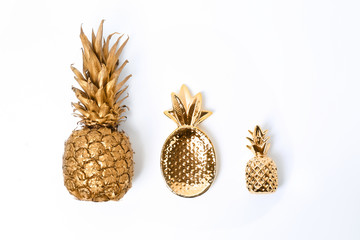 Composition with different gold pineapples on white background, top view