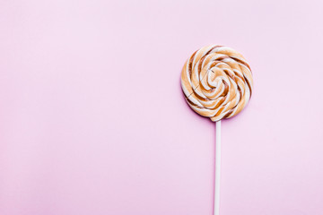 Caramel lollipop on pink background. Flat lay. Minimal concept.