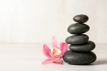 Naklejka na ściany i meble Stack of spa stones and flower on table against white background, space for text