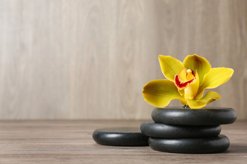 Spa stones and flower on wooden table, space for text