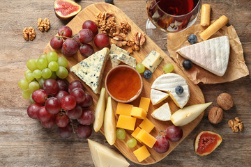 Fototapeta Flat lay composition with board of delicious cheese and snacks on wooden background obraz