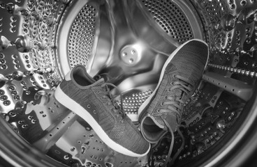 Sports sneakers in metal drum of washing machine close-up. Wide angle photo