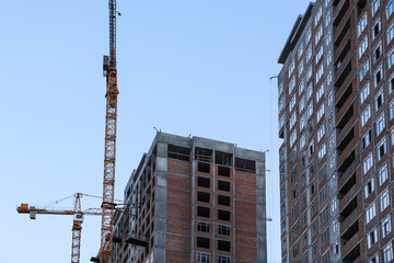 Fototapeta na wymiar Construction crane and unfinished building against blue sky
