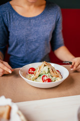 Obraz na płótnie Canvas Woman's hands with Caesar salad on table in restaurant. Healthy food concept.