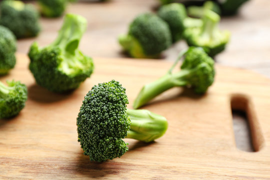 Wooden board with fresh broccoli florets on table, closeup. Space for text