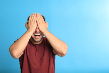 Young man being blinded on blue background, space for text