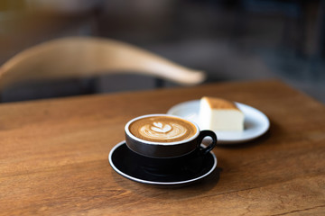 latte art and cheesecake on wooden table , coffee cafe background