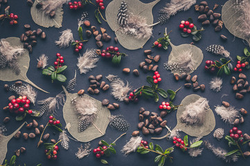 Wild forest pattern. Dry leaves, lingonberry berries, pine nuts, quail feathers on a black...