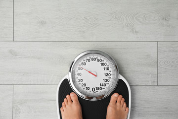 Woman standing on scales indoors, top view with space for text. Overweight problem