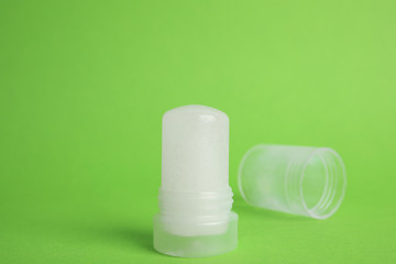 Natural crystal alum stick deodorant and cap on green background