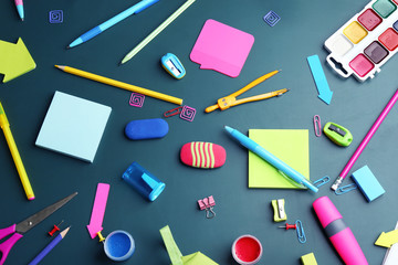 Different bright school stationery on green background, flat lay