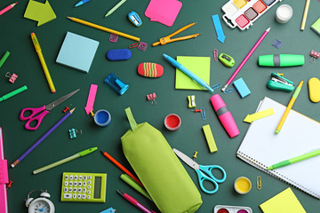 Different bright school stationery on green background, flat lay