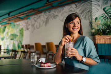 Portrait photo of a beautiful woman smiling and holding cold coffee.
