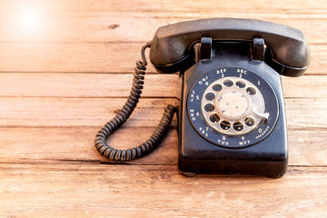 Retro rotary black telephone on wood table background. Old telephone with rotary dial.