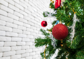 Christmas tree decorated with Red balls toys on a white wall, copy space.