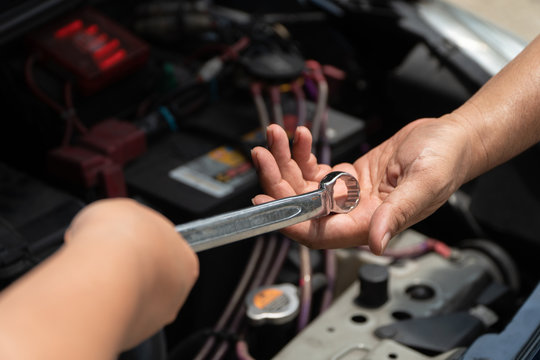 The head of technician the car engine repairman service is sending a wrench to the co-worker. Concept of maintenance vehicle mechanic and automotive
