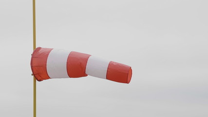 Frayed windsock in moderate wind against blue sky