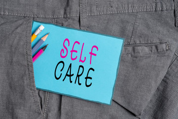 Conceptual hand writing showing Self Care. Concept meaning the practice of taking action to improve one s is own health Writing equipment and blue note paper in pocket of trousers