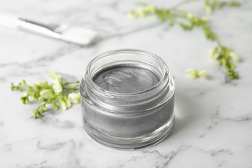 Professional face mask and flowers on white marble table