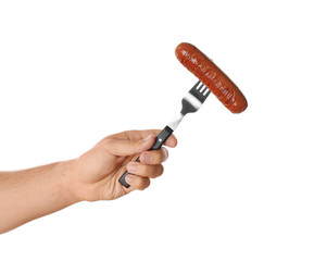 Man holding fork with grilled sausage on white background, closeup. Barbecue food