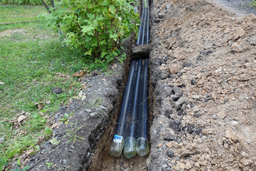 Three plastic water pipes in the pit, during repair work.